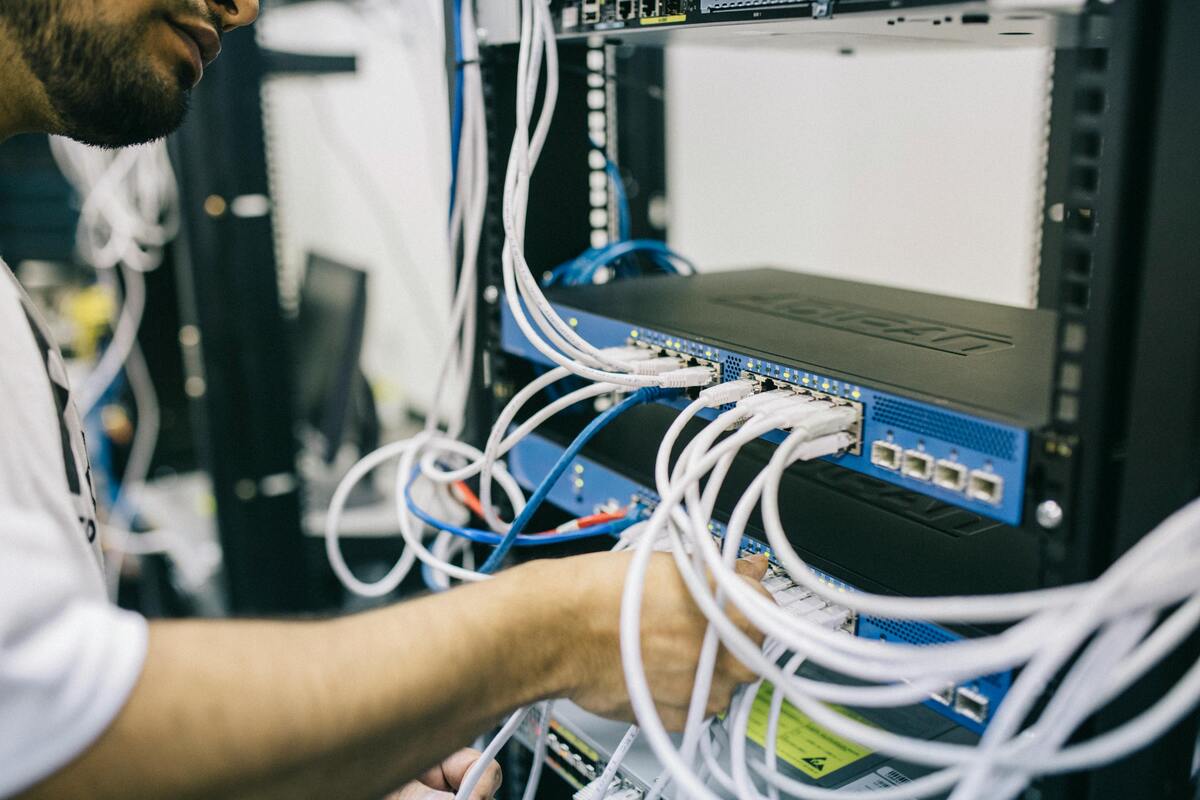 An IT professional configuring network cables in a server rack